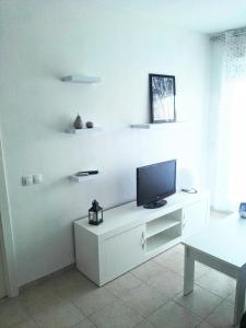 sala de estar con TV en una pared blanca en Apartamento Ariel en Peñíscola