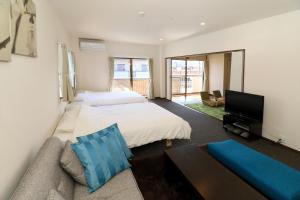 a bedroom with two beds and a couch and a tv at Fuji scenic house 73 in Fujikawaguchiko
