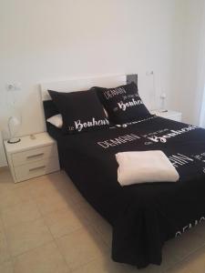 ein schwarzes Bett mit schwarzen und weißen Kissen darauf in der Unterkunft Apartamento Ariel in Peñíscola