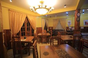 a restaurant with wooden tables and chairs and a chandelier at ABC Guest Inn & Restaurant in Haputale