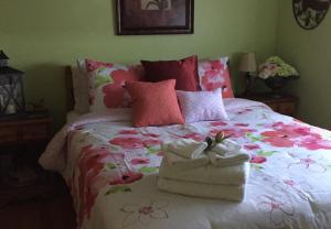 Un dormitorio con una cama con flores rosas y toallas. en Paola Beauty Farm B&B and Day Spa, en Dalroy