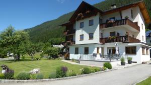a large white building with a lawn in front of it at Pension Haus Edelweiss in Weissensee