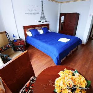 a bedroom with a bed and a table and a tower at Hostal Arauco in Otavalo