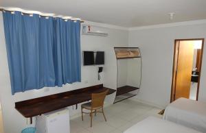 a room with a desk and a blue curtain at Hotel Monte Carlo Uberlândia in Uberlândia