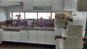 a kitchen with white cabinets and a sink and a refrigerator at Paraiso dentro da cidade in Serra Negra