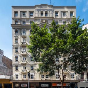 a white building with a tree in front of it at Cinelandia Hotel in Sao Paulo