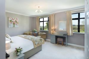 a bedroom with a bed and a desk and window at Stanton Manor Hotel in Chippenham