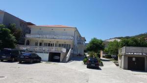 una gran casa blanca con coches aparcados en una entrada en Anka Bunić, en Rab