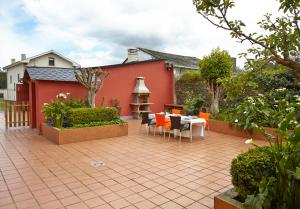 a patio with a table and chairs in front of a red house at Casa Samuel in Navia