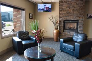 a living room with two chairs and a fireplace at BCMInns - Lloydminster in Lloydminster