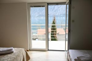 una camera da letto con porta scorrevole in vetro che si apre su un balcone di Ruža Apartments a Kotor (Cattaro)