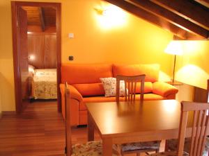 Una sala de estar con un sofá naranja y una mesa. en Aparthotel Santa Marina, en Cuéllar