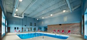 a large pool in a building with red chairs at Ramada by Wyndham Trenton in Trenton