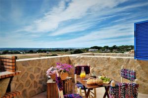 un patio con mesa y sillas en una pared de piedra en Siamoformentera Donatella en Sant Ferran de Ses Roques