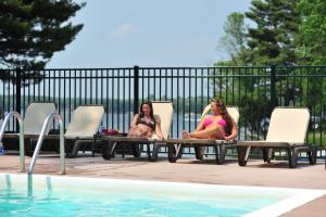 two women sitting in chairs next to a swimming pool at Bakers Sunset Bay Resort in Wisconsin Dells