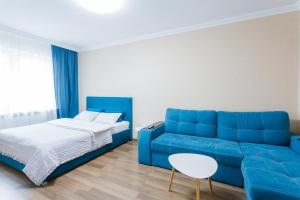 a blue couch and a bed in a room at Cosy Apartment at Pozniaky in Kyiv