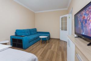 キーウにあるCosy Apartment at Pozniakyのリビングルーム(青いソファ、薄型テレビ付)