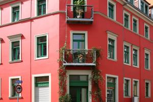 a red building with a dog in a balcony at Übernachtenindresden in Dresden