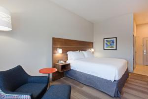 a hotel room with a bed and a chair at Holiday Inn Express & Suites Corona, an IHG Hotel in Corona
