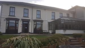 een wit gebouw met zwarte ramen en een bank bij The Marquis Inn in Aberdare