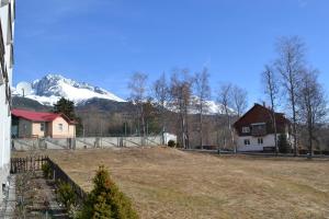 een tuin met een huis en een met sneeuw bedekte berg bij Apartment Lucy in Vysoké Tatry