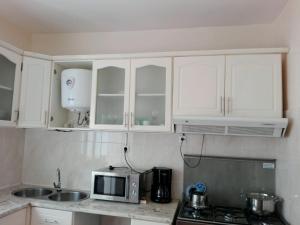 a kitchen with white cabinets and a microwave at Casa Mendes in Tarrafal