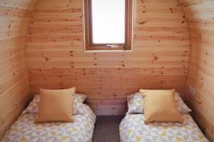 two beds in the corner of a log cabin with a window at Howe of Torbeg in Ballater
