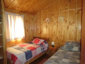 una camera con due letti in una baita di legno di Cabañas Antilhue a Olmué