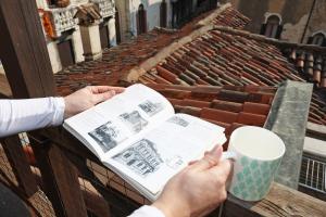 a person reading a book and a cup of coffee at Ca Barbaro -appartamenti storici- in Venice