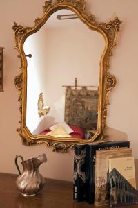 a mirror sitting on top of a table with books at Ca Barbaro -appartamenti storici- in Venice