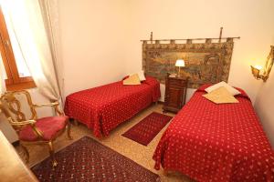 a bedroom with two red beds and a chair at Ca Barbaro -appartamenti storici- in Venice