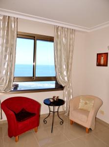 a living room with a red chair and a window at Apartments on the Beach in Haifa