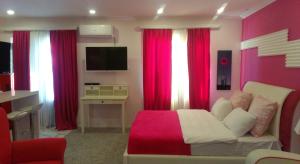 a bedroom with red curtains and a couch and a tv at Pink Apartment near Airport in Nizhnyaya Alekseyevka
