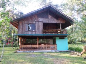 een klein houten huis met een balkon in een veld bij Hotel & Cabinas Nadine in Cahuita