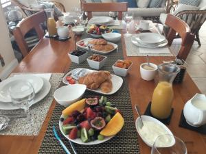 a table topped with plates of food and fruit at Brezza Bella Boutique Bed & Breakfast in Merewether