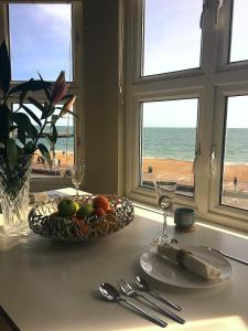 a table with a bowl of fruit on a table with the beach at Stones Throw From The Beach - Stunning Sea View in Portsmouth