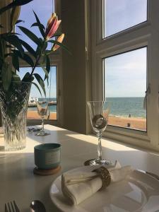 a table with a plate and wine glasses and a window at Stones Throw From The Beach - Stunning Sea View in Portsmouth