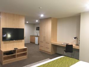 a living room with a television and a desk with a chair at Greenlane Suites in Auckland