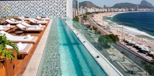 uma piscina do hotel com espreguiçadeiras e uma praia em Emiliano Rio no Rio de Janeiro