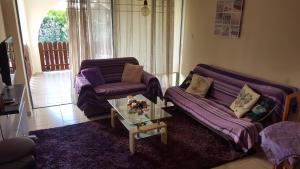 salon z 2 fioletowymi kanapami i stołem w obiekcie Abitare cosy apartment w Pafos