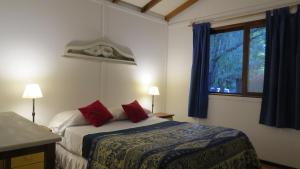 um quarto com uma cama com almofadas vermelhas e uma janela em Cabañas Del Potrero em Ocean Park
