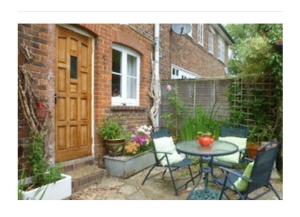 een terras met een tafel en stoelen voor een huis bij Court Barn Cottage B&B in Burwash +7 foto's