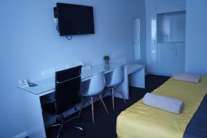 a room with a bed, desk, chair and television at Oasis Motel in Cobar