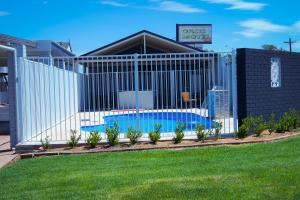 a building with a fence and a sign on the side of it at Oasis Motel in Cobar