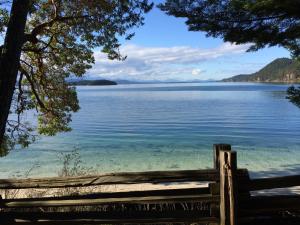 a view of a lake from a wooden fence at Sticks and Stones Cottage-Arbutus Grove in Galiano