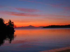 einen Sonnenuntergang über einem Wasserkörper in der Unterkunft Sticks and Stones Cottage-Arbutus Grove in Galiano