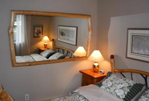 a bedroom with two beds and a mirror at Sticks and Stones Cottage-Arbutus Grove in Galiano