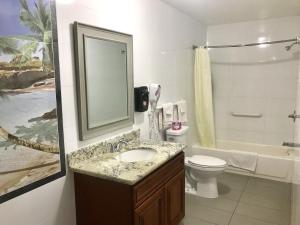 norwalk inn & suites في نورووك: حمام مع حوض ومرحاض ومرآة
