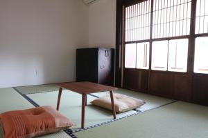 Zimmer mit einem Tisch, einem Bett und einer Tür in der Unterkunft Yanagawa B&B hatago in Yanagawa