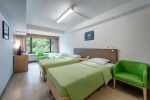 a hospital room with four beds and green chairs at YHA Mei Ho House Youth Hostel in Hong Kong